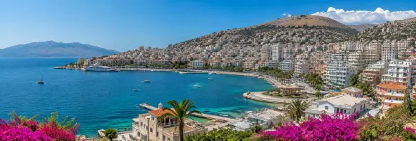 Sarandë, Albania, with turquoise Ionian Sea waters, a coastal promenade, marina and hillside cityscape.