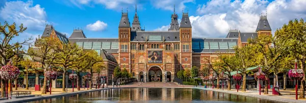 Rijksmuseum in Amsterdam with its historic façade, reflecting pool, and clear blue sky.
