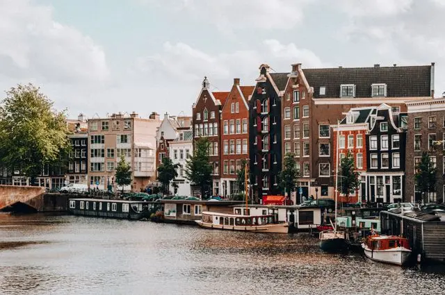 Historic canal houses and houseboats along Amsterdam's Canal Ring on a calm day.