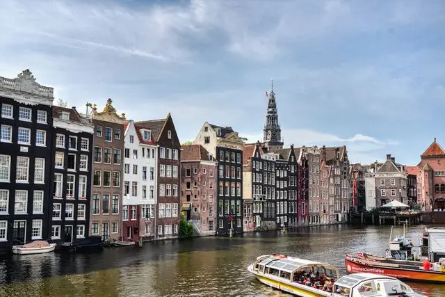Canal cruise boat passing historic buildings along Amsterdam's Canal Ring.