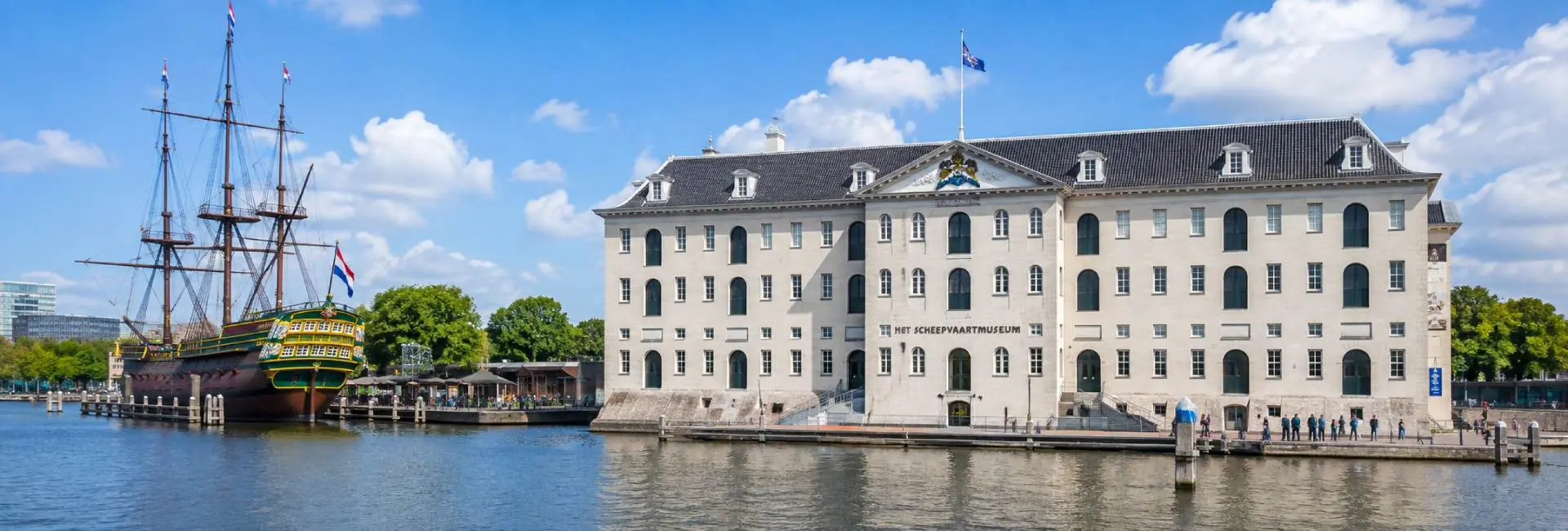 The National Maritime Museum in Amsterdam beside the Oosterdok waterfront with a historic sailing ship
