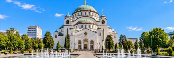 Church of Saint Sava in Belgrade, Serbia, featuring its grand white facade, green domes and beautiful fountains.