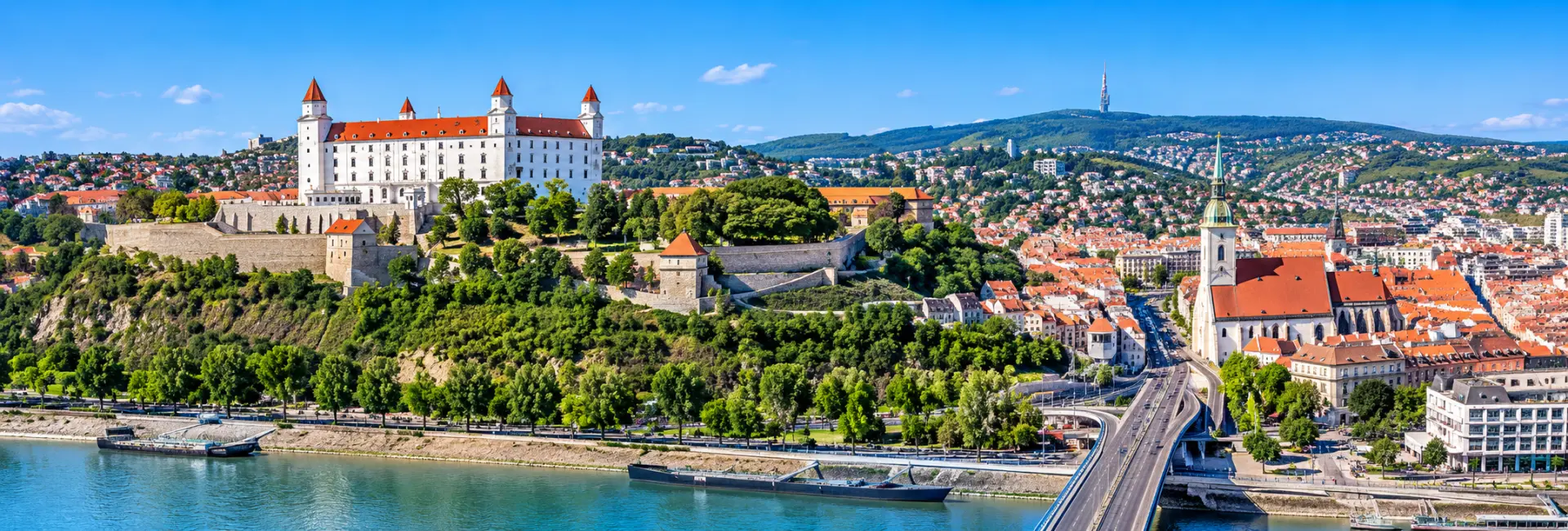 Panoramic view of Bratislava Castle overlooking the Danube River and historic city center in Slovakia.
