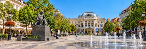 Hviezdoslav Square in Bratislava with its historic buildings, fountains, trees, and Hviezdoslav statue.