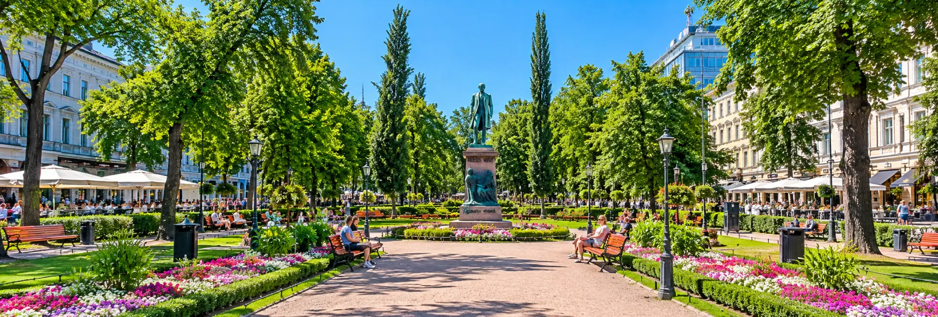 Esplanadi Park in Helsinki, Finland, featuring tree-lined walkways, flower beds, and the Alexis Kivi statue.