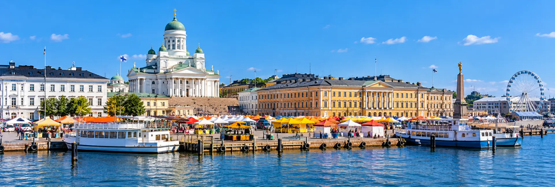 Market Square (Kauppatori) in Helsinki with colorful market stalls, boats, and historic waterfront buildings.