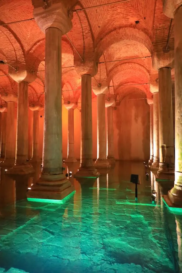 Basilica Cistern interior with tall stone columns, brick arches, and turquoise-lit water.