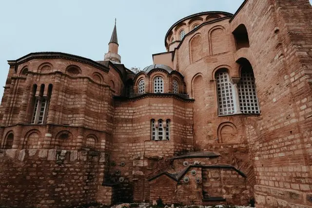 Exterior of Chora Church in Istanbul, showing its historic Byzantine brickwork, arches, windows, and dome.