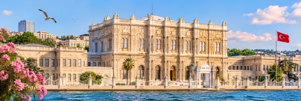 Dolmabahçe Palace on the Bosphorus in Istanbul, with its ornate façade, gardens, and Turkish flag.