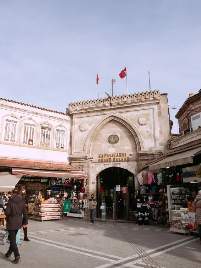 Historic entrance to Istanbul’s Grand Bazaar with Turkish flags and surrounding shops.