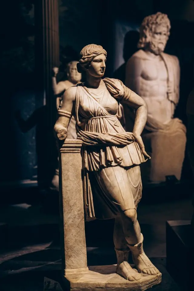 Classical marble statue of a woman displayed among ancient sculptures.