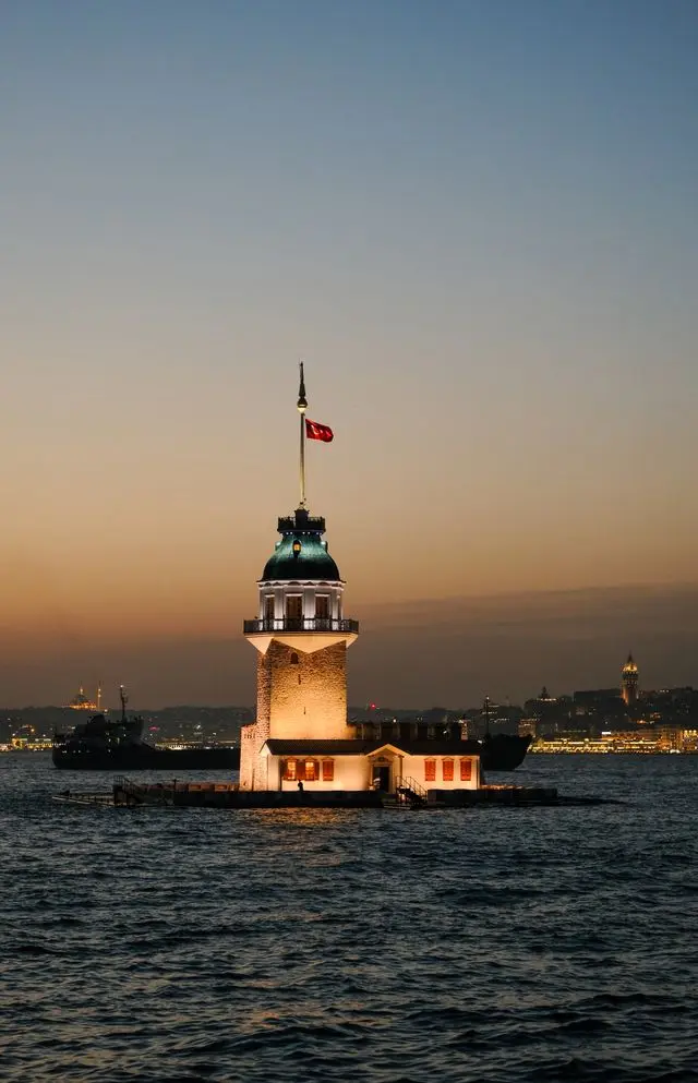 Illuminated Maiden’s Tower at dusk, surrounded by the waters of the Bosphorus.