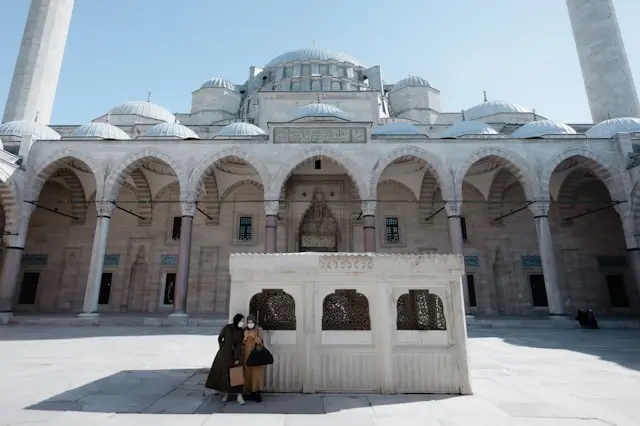 Courtyard of Süleymaniye Mosque with its central fountain, domes, arches, and towering minarets.