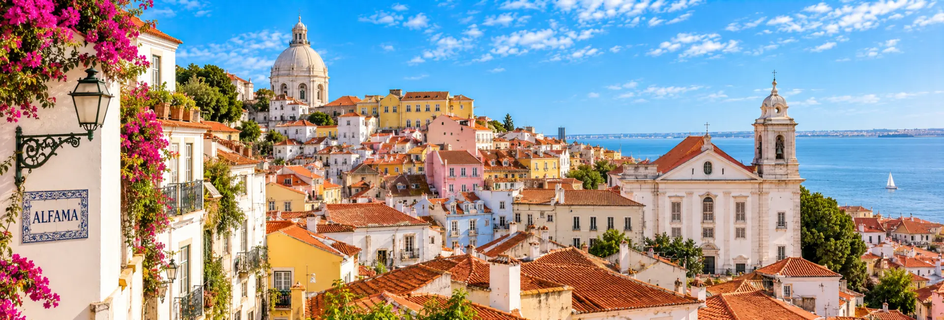Alfama District in Lisbon, Portugal, with colorful hillside homes, terracotta roofs, and historic streets.