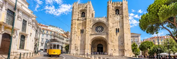 Lisbon Cathedral in Portugal, with its Romanesque façade and iconic twin towers overlooking a historic street.