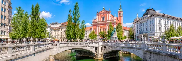 Triple Bridge (Tromostovje) spanning the Ljubljanica River in Ljubljana, Slovenia, with historic buildings.