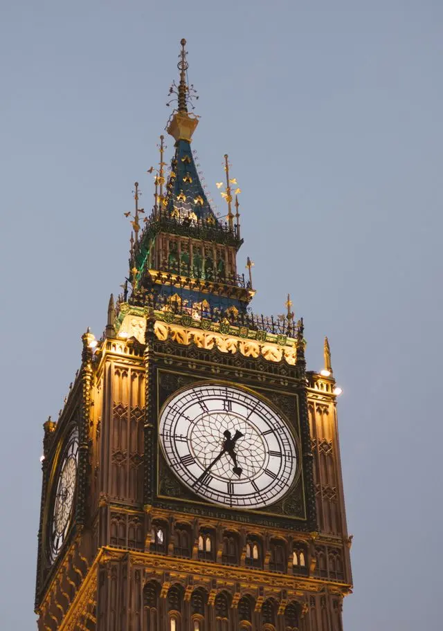 Illuminated Big Ben clock tower glowing against the evening sky in London.