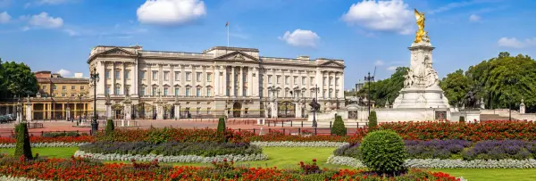 Buckingham Palace and the Victoria Memorial viewed from the gardens on a bright sunny day in London.
