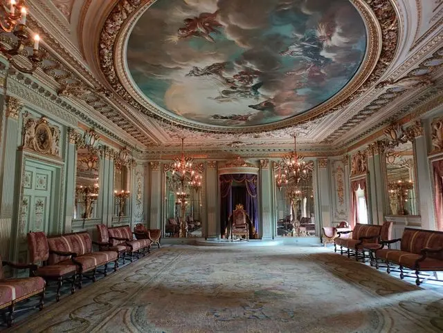 State room inside Buckingham Palace featuring ornate ceiling artwork, chandeliers, and elegant royal furnishings.