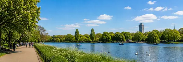 Hyde Park London with the Serpentine lake, lush greenery, boats and blue sky