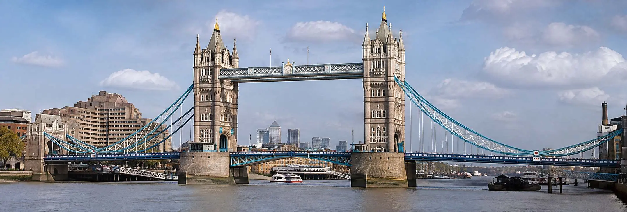 Tower Bridge in London viewed from the River Thames on a bright, clear day with the city skyline in the background.