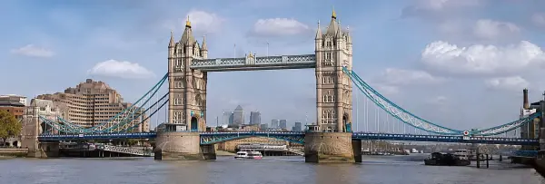 Tower Bridge in London viewed from the River Thames on a bright, clear day with the city skyline in the background.