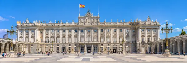 Royal Palace of Madrid with its grand façade and expansive courtyard under a blue sky