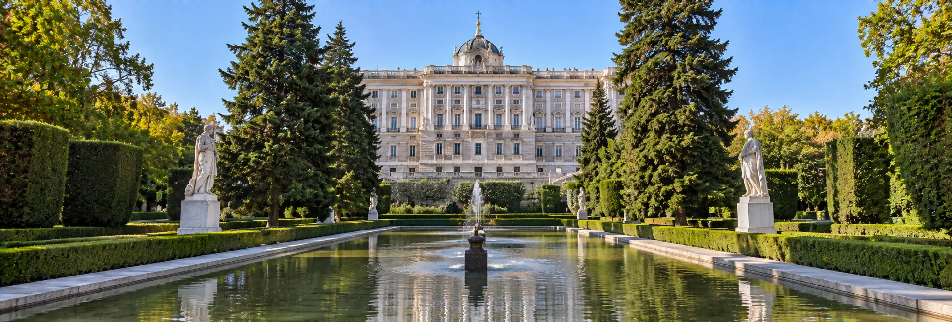 Sabatini Gardens in Madrid with manicured hedges, statues, fountain, and Royal Palace