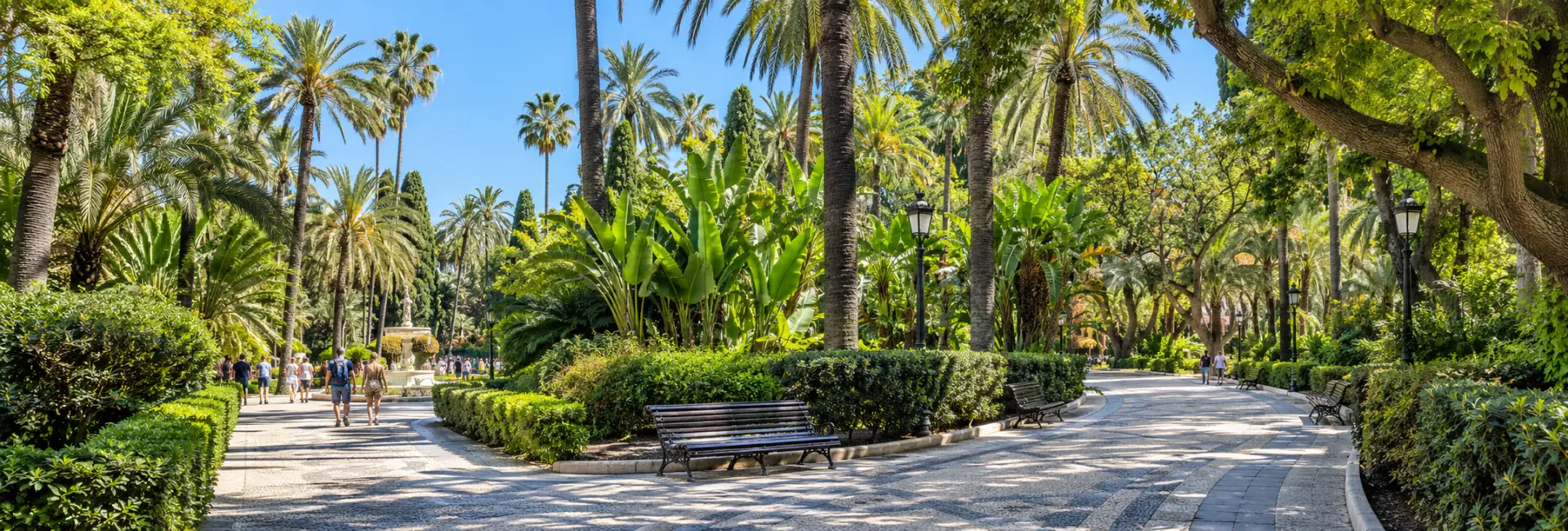 Málaga Park with shaded paths, tall palms, lush foliage and benches.