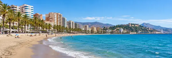 Playa de la Malagueta with sandy shores, blue sea and palm-lined beachfront buildings.