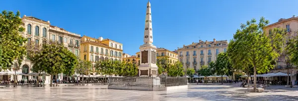Plaza de la Merced in Málaga with the Torrijos obelisk and surrounding historic buildings.