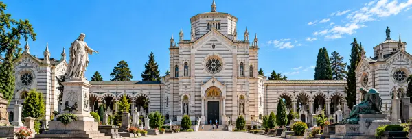 Monumental Cemetery in Milan with ornate striped architecture, sculptures, arches and landscaped tombs.