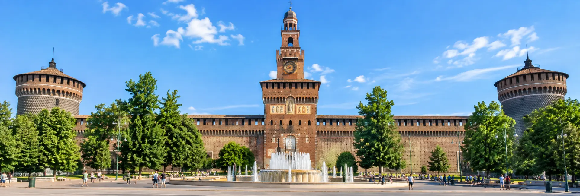 Sforza Castle in Milan with its historic brick walls, towers and central clock tower under a blue sky.