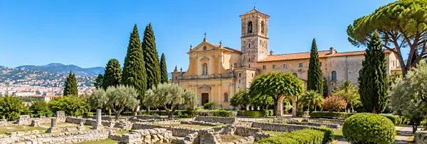 Cimiez Monastery in Nice, France, surrounded by historic ruins, cypress trees, and Mediterranean gardens.