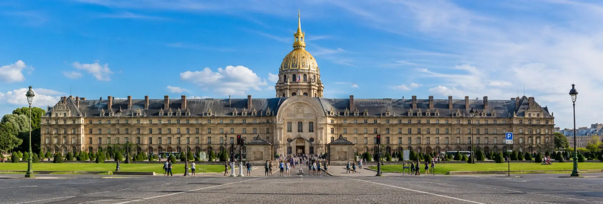 Les Invalides in Paris with its grand façade and iconic gilded dome under a blue sky.