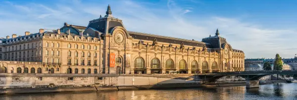 Musée d'Orsay museum on the Seine River in Paris under a clear blue sky with its iconic clock tower.