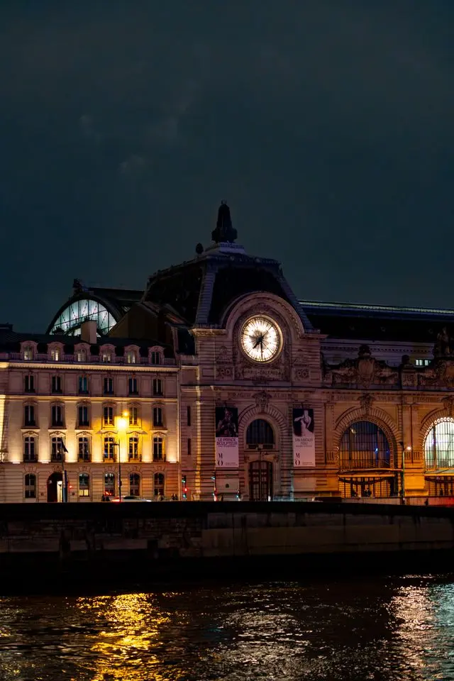 Night view of the illuminated Musée d'Orsay along the Seine River in Paris, France.