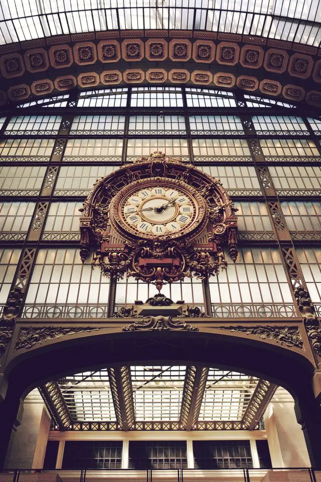Close-up of the iconic historic clock inside Musée d'Orsay framed by its grand glass architecture.