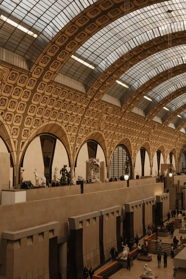 Grand interior gallery of Musée d'Orsay featuring sculptures beneath its iconic vaulted glass ceiling.