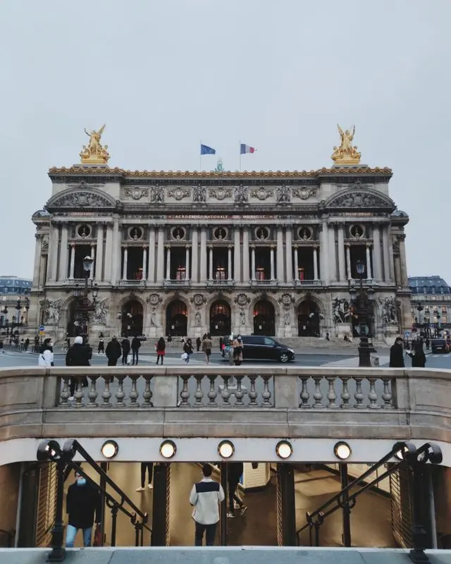 Front view of Palais Garnier in Paris with its grand Beaux-Arts façade and Opera Metro entrance.