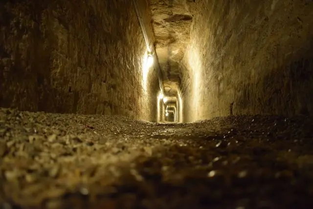 Low-angle view of a long stone tunnel inside the Paris Catacombs