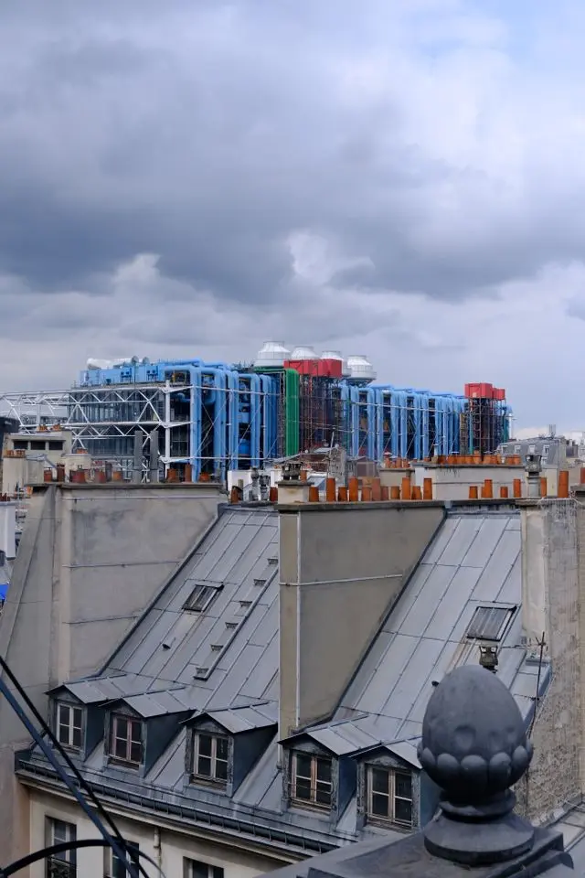 Centre Pompidou visible above traditional Parisian rooftops under a cloudy sky