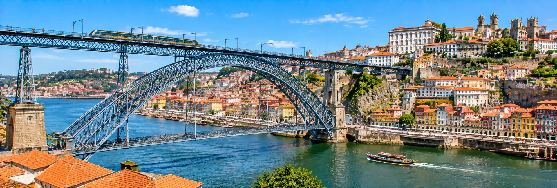 Dom Luís I Bridge in Porto, Portugal, spanning the Douro River with colorful historic buildings along the waterfront.