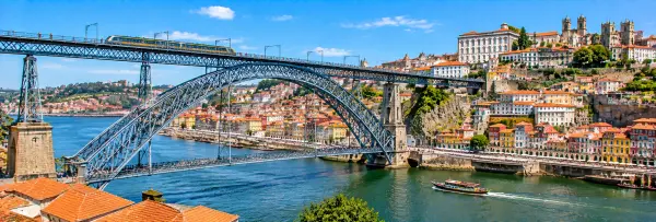 Dom Luís I Bridge in Porto, Portugal, spanning the Douro River with colorful historic buildings along the waterfront.