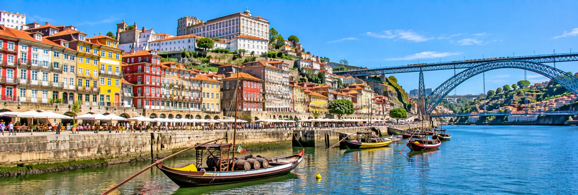 Ribeira District in Porto, Portugal, with colorful riverside buildings, traditional boats, and Dom Luís I Bridge.