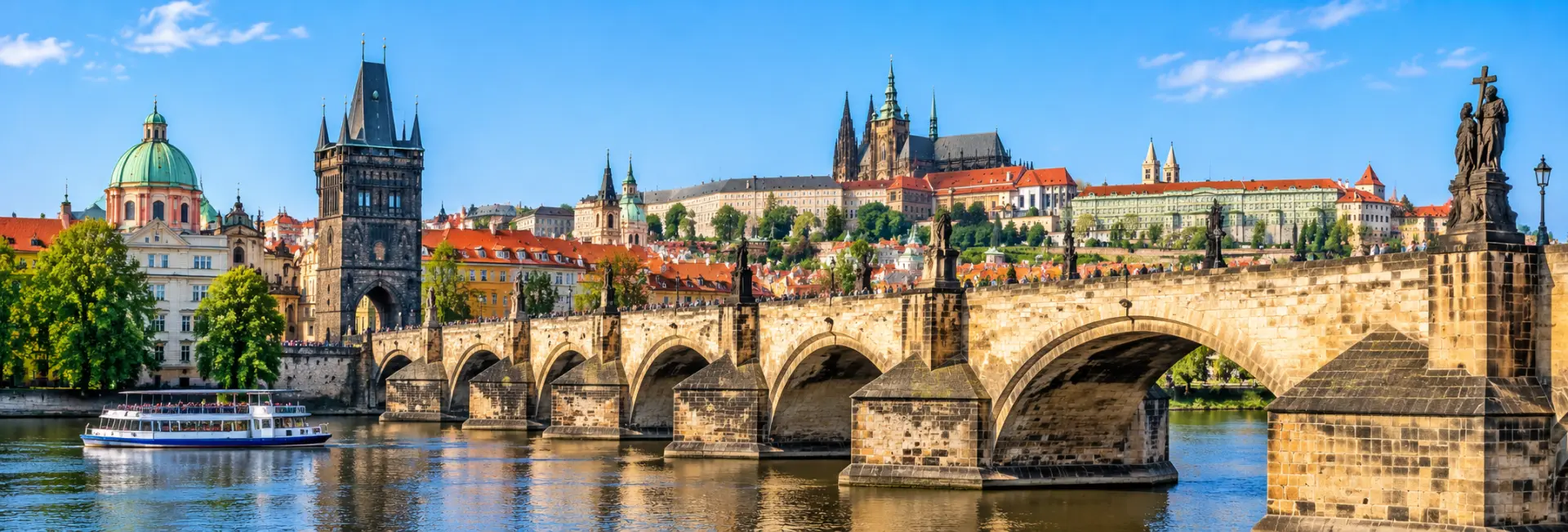 Charles Bridge spanning the Vltava River with Prague Castle and historic rooftops in the background