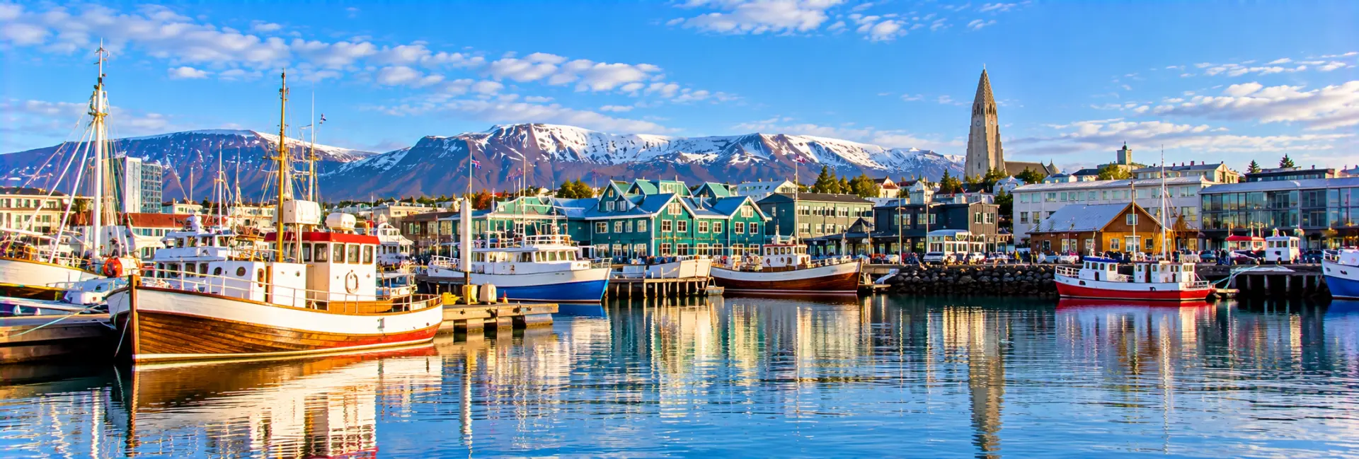 Reykjavík Old Harbour with colorful boats, waterfront buildings and snowy mountains