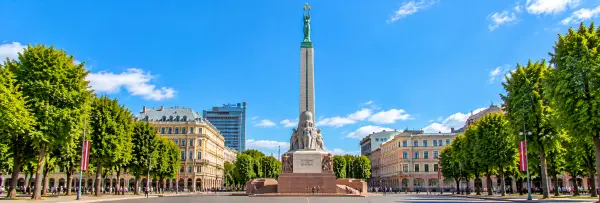 Freedom Monument in Riga, Latvia, featuring a towering stone column topped with a woman holding three golden stars.