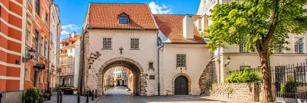 Swedish Gate in Riga, Latvia, featuring a historic stone archway, cobblestone street and medieval Old Town buildings.