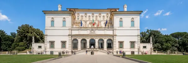 Galleria Borghese museum in Rome with ornate façade, lawns, trees and visitors